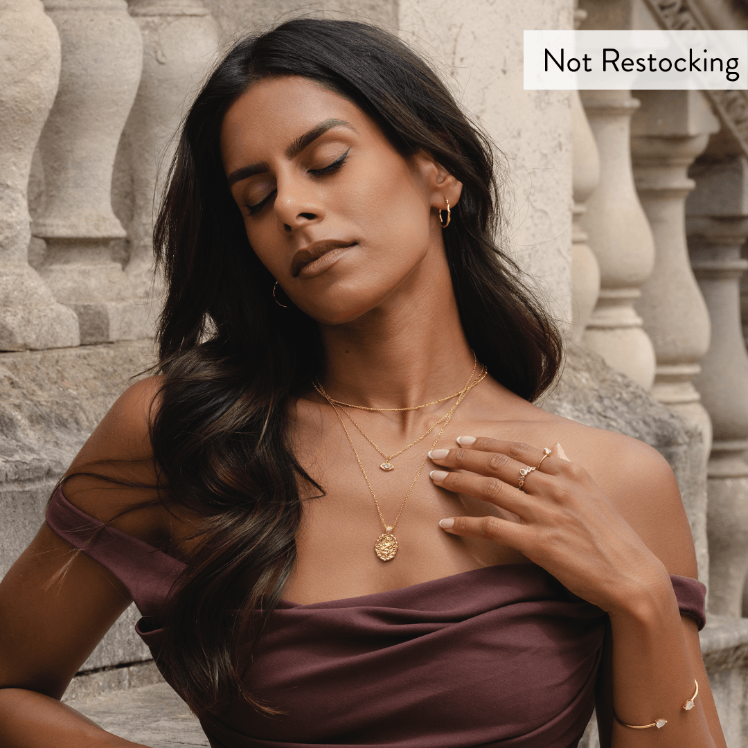 Limited Edition Goddess Saraswati Blue Topaz Necklace worn with layered gold jewellery and elegant occasion styling.