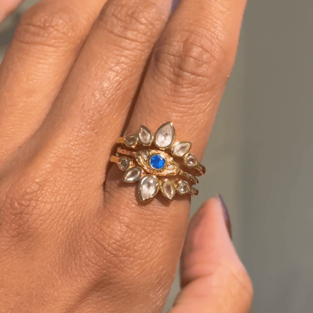 3 ring stacked with a central gold evil eye ring and 2 lotus gold rings with rose quartz and white topaz