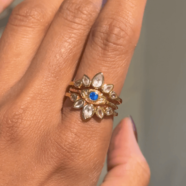 3 ring stacked with a central gold evil eye ring and 2 lotus gold rings with rose quartz and white topaz