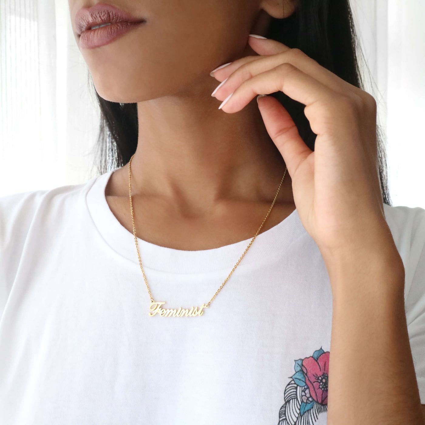 Woman wearing gold feminist script name necklace with frida kahlo feminist t-shirt.