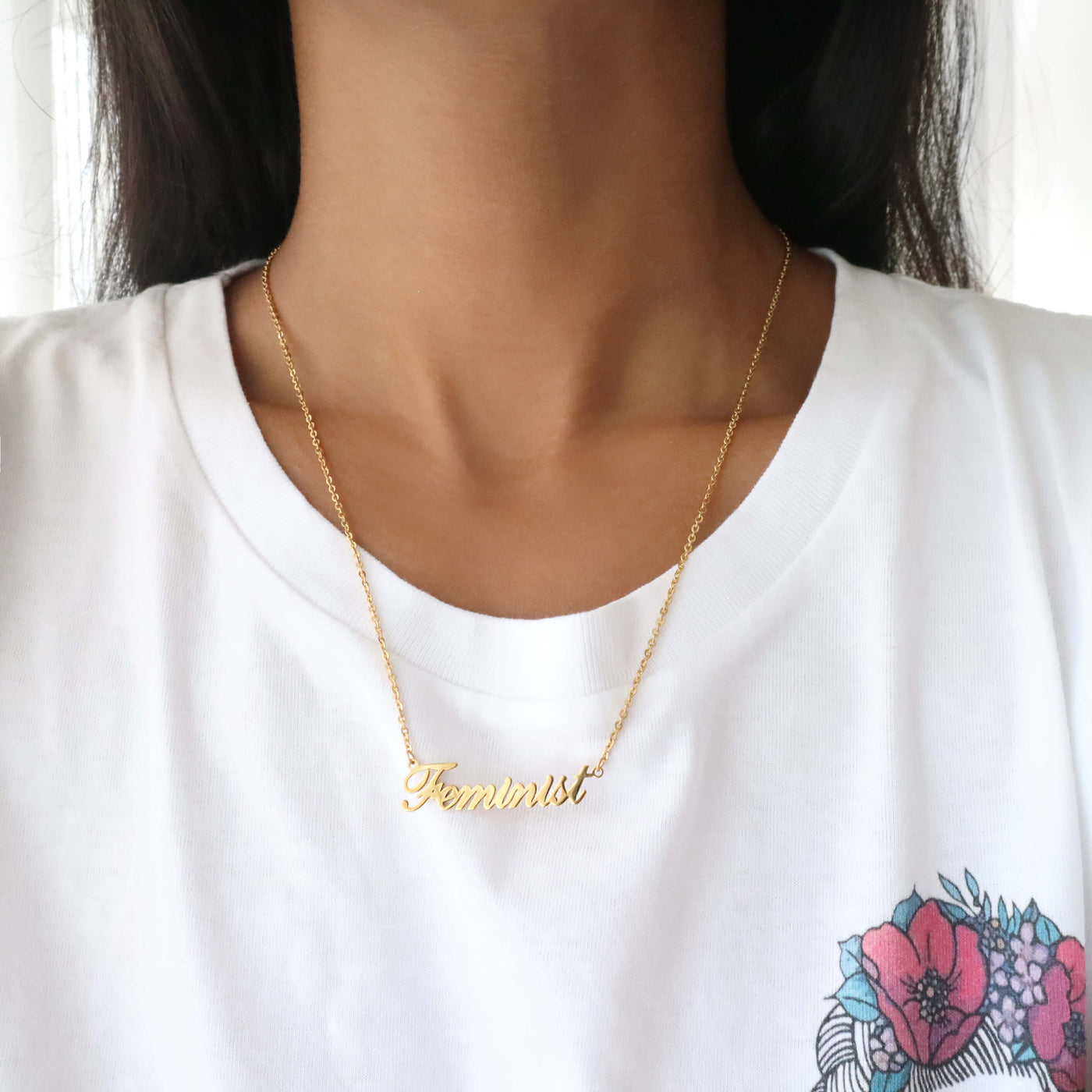 Woman wearing gold feminist script name necklace with frida kahlo feminist t-shirt