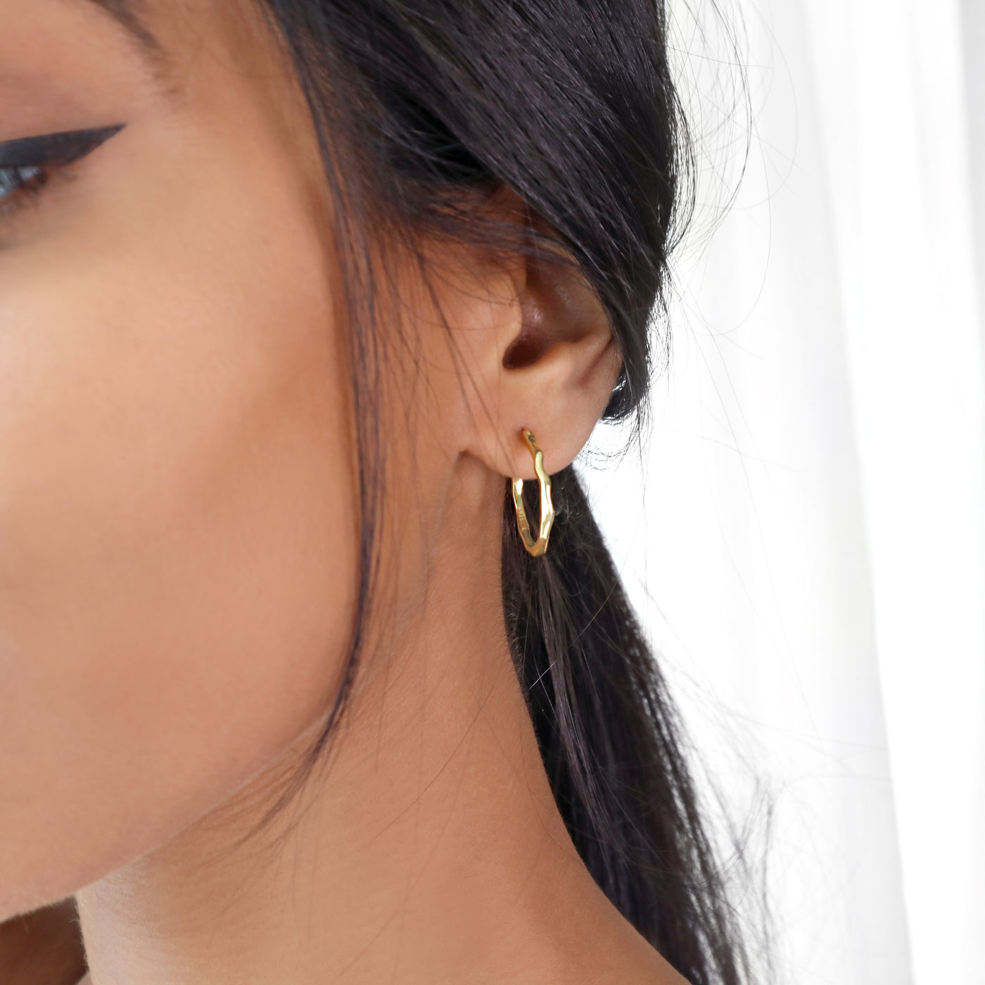 Woman wearing minimal irregular gold hoop earrings. Earring width & height: 2cm.Material: 18k gold-plated 925 sterling silver